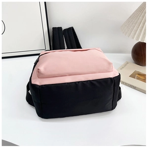 Detailed view of a pink and black color-block nylon backpack on a white desk