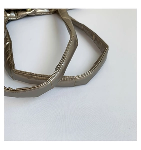 Detail view of padded quilted shoulder straps on a shiny bronze waterproof tote bag