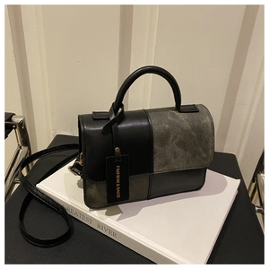 Detail of a chic patchwork handbag in black leather and grey canvas with a metal clasp