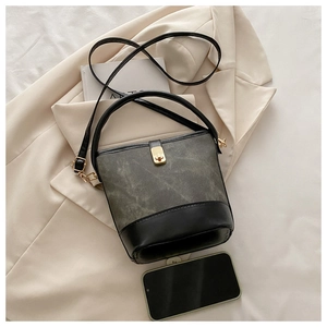 Close-up of retro bucket bag in grey-green suede and black leather with gold lock
