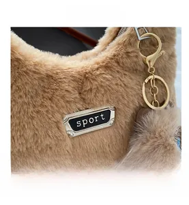 Détail du sac à main en fausse fourrure marron avec plaque sport et métal doré