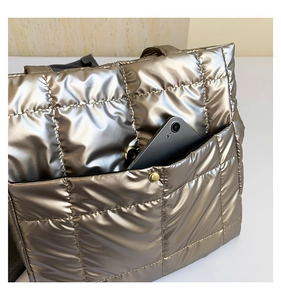 Detail of quilted metallic tote bag with front pocket showing smartphone storage capacity