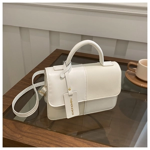 Close-up of white stitched crossbody bag on a cafe table with minimalist design