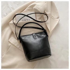 Close-up of black leather bucket bag with matte texture and elegant gold hardware