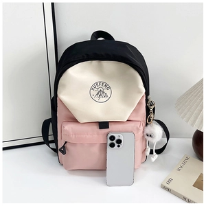 Close-up of color-block nylon backpack with plush charm and side smartphone size reference