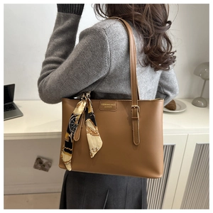 Detail of brown leather tote bag with decorative printed scarf on the handle