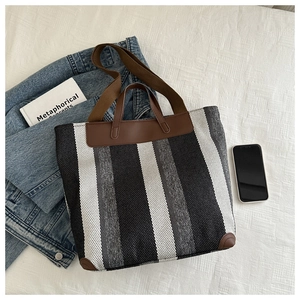 Detailed top view of a striped woven tote bag with leather straps and lifestyle accessories