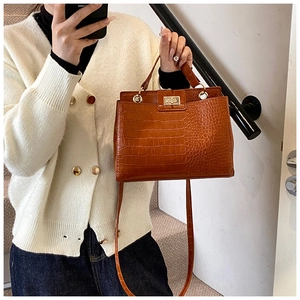 Close-up of brown crocodile pattern crossbody bag with golden metal twist lock