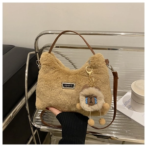 Détail du sac à main en peluche marron avec logo sport en métal et breloque ours