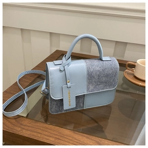 Detail of light blue patchwork handbag with premium leather and denim texture on a table