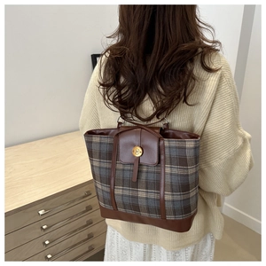 Dettaglio della borsa tote vintage a quadri con finiture in pelle marrone e fibbia dorata