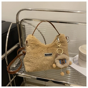 Gros plan d'un sac à main en peluche marron clair avec plaque sport et breloque ours