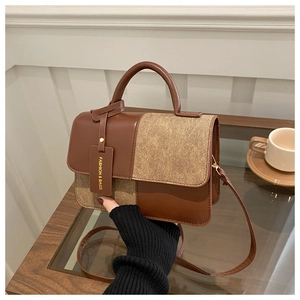 Detailed view of the patchwork handbag with top handle and strap on a wooden table