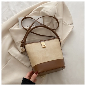 Detail view of canvas bucket bag with brown leather trim and golden metal lock