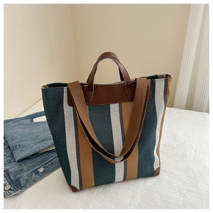 Detail of vintage striped canvas tote bag with brown faux leather trim and wide shoulder strap