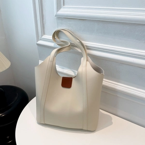 Detail of cream tote bag with brown leather buckle and reinforced handle stitching
