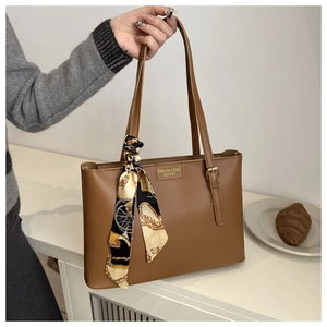 Détail du sac cabas en cuir marron avec anse en foulard de soie et logo embossé