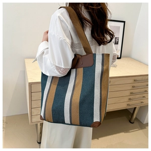Detail of leather reinforced handles and canvas stripes on a large shoulder tote bag