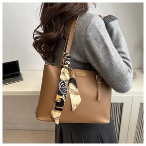 Close-up of brown leather tote bag with silk scarf accent and fashion lettering detail
