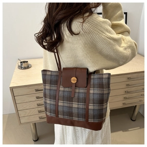 Detail of vintage plaid tote bag with brown leather accents and metal buckle on the shoulder