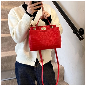 Detail of red crocodile embossed leather handbag with gold metal twist lock and top handle