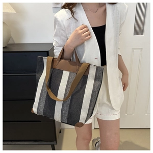 Detailed shot of large striped tote bag with brown leather handles and reinforced corners