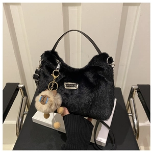 Détail du sac à main noir en peluche avec étiquette sport et pendentif ours décoratif