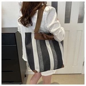 Detail of striped canvas tote bag showing brown leather handles and spacious interior capacity