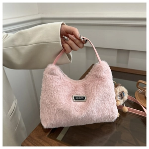 Détail d'un sac à main rose en fausse fourrure avec pendentif animal et plaque métallique
