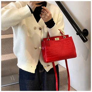Close-up of red crocodile embossed tote bag featuring gold clasp and textured PU leather
