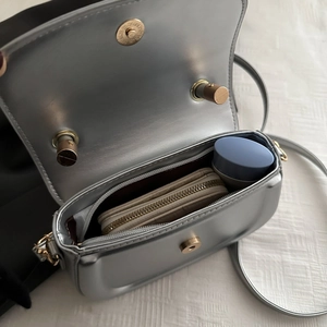 Silver PU leather saddle bag showing internal storage capacity with shoulder strap
