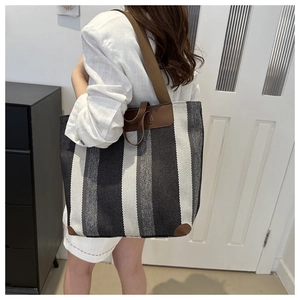 Detail of a large striped canvas tote bag showing its spacious design and brown leather trims