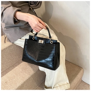 Détail du sac à main en cuir noir à motif crocodile avec fermoir rotatif en métal doré