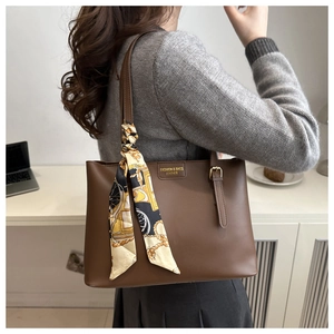 Close-up of retro brown PU leather tote bag featuring fashion metal plaque and silk scarf