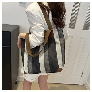 Detail of striped tote bag showing durable brown shoulder straps and fabric texture