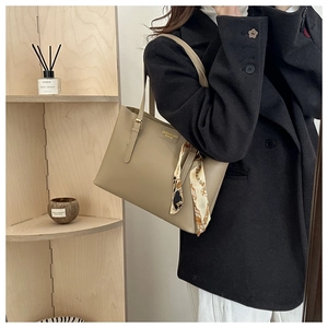 Detail of camel leather tote bag featuring an elegant printed scarf on the handle