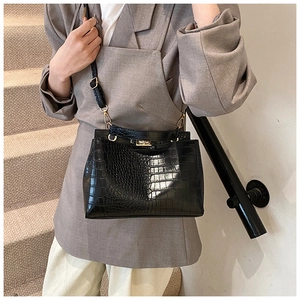 Détail du sac noir motif crocodile avec fermoir rotatif doré élégant et finitions métalliques