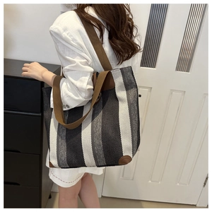 Detail shot of striped tote bag with brown reinforced corners and woven handles