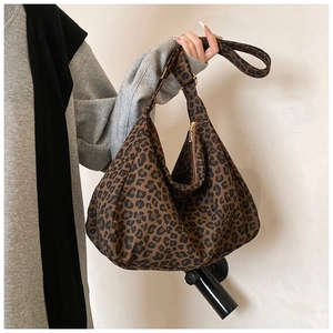 Detail of leopard print canvas tote bag featuring a spacious crescent shape and gold zipper