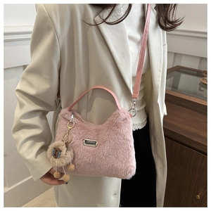 Détail d'un sac demi-lune rose en peluche avec plaque sport et breloque mouton mignonne