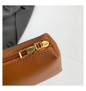 Detail of premium golden metal zipper and precise stitching on brown faux leather bag