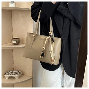 Macro shot of khaki leather tote bag with elegant silk scarf wrap on the handle