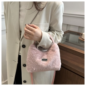 Détail du sac à main rose en fausse fourrure avec plaque sport noire et lanière
