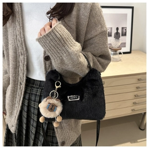 Détail du sac à main en peluche noire avec étiquette sport et breloque ours kaki