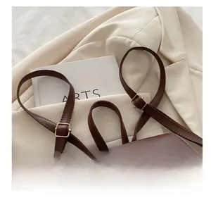 Détail de la bandoulière du sac à dos en cuir marron avec boucle en métal doré élégante