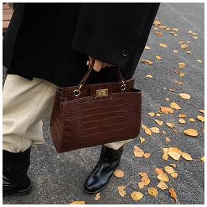 Détail du sac à main marron foncé en cuir embossé crocodile avec fermoir doré rotatif