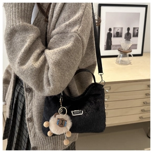 Détail du sac à main en peluche noire avec plaque sport et breloque petit ours