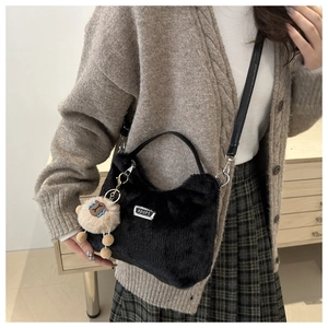 Détail du sac à main en peluche noire avec plaque sport et breloque animalière