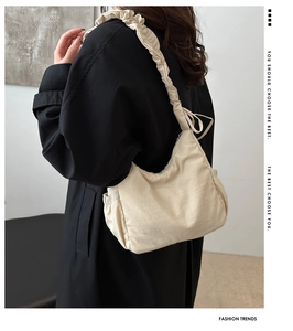 Detail of ruffled shoulder strap on a beige nylon crossbody bag with pleated texture