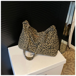 Detailed close-up of leopard print tote bag featuring a bronze metal zipper closure